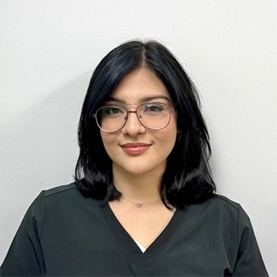 Janett O. smiling in glasses.